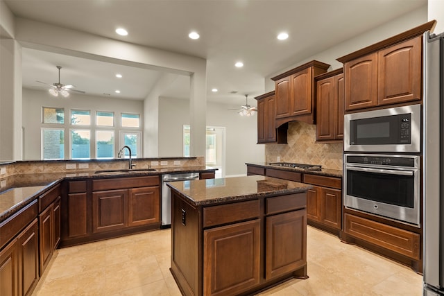 kitchen featuring sink, stainless steel appliances, backsplash, kitchen peninsula, and dark stone countertops