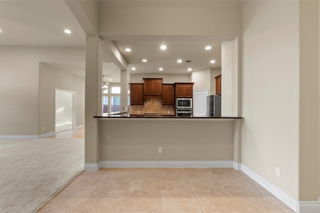 kitchen featuring kitchen peninsula, decorative backsplash, stainless steel appliances, light colored carpet, and sink