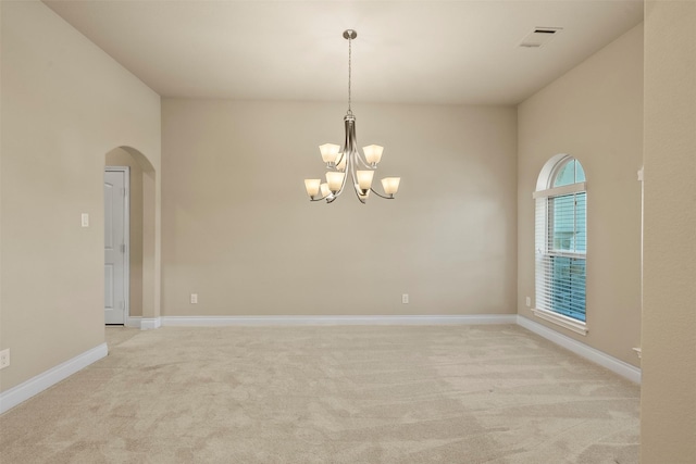 unfurnished room with visible vents, baseboards, light carpet, arched walkways, and a notable chandelier