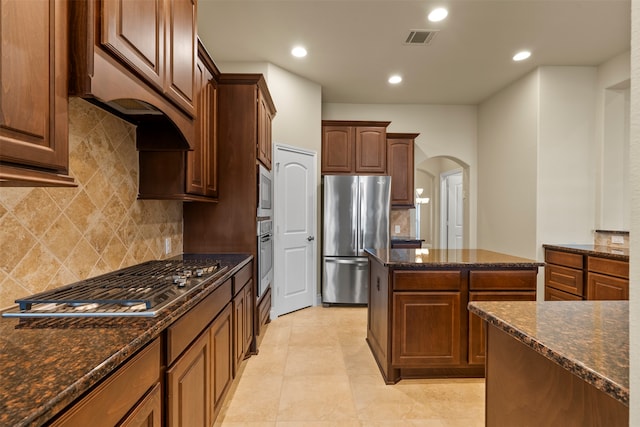 kitchen featuring decorative backsplash, a kitchen island, dark stone countertops, and stainless steel appliances