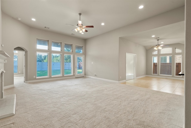 unfurnished living room with ceiling fan, a fireplace, and light colored carpet