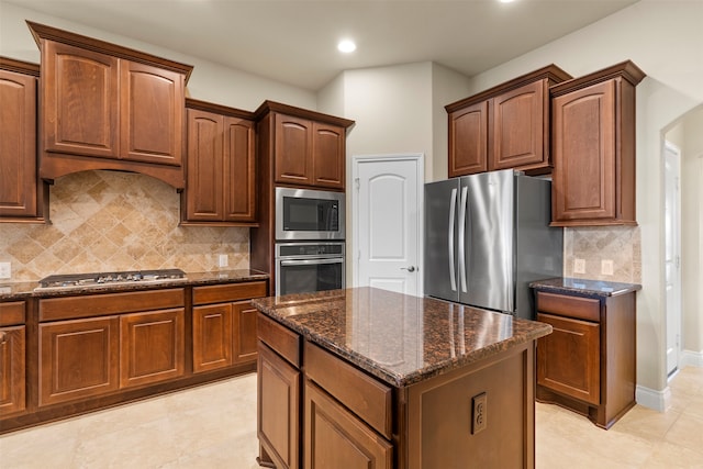 kitchen featuring backsplash, dark stone countertops, a kitchen island, and stainless steel appliances