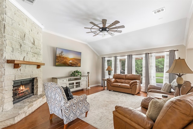 living room featuring ceiling fan, a stone fireplace, crown molding, hardwood / wood-style floors, and vaulted ceiling