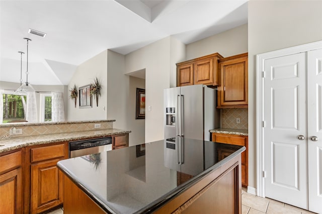 kitchen featuring appliances with stainless steel finishes, backsplash, pendant lighting, a kitchen island, and light tile patterned flooring