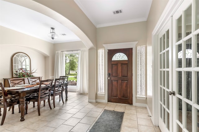 foyer with light tile patterned floors and crown molding