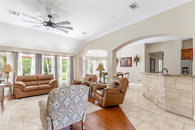 living room with light wood-type flooring, crown molding, ceiling fan, and lofted ceiling