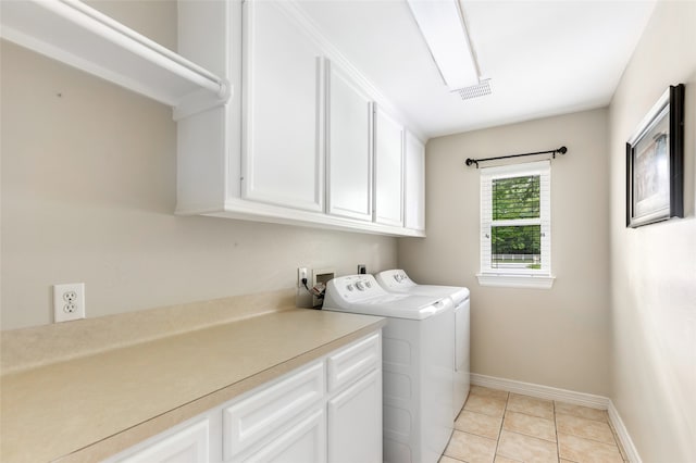 clothes washing area featuring washing machine and clothes dryer, light tile patterned floors, and cabinets