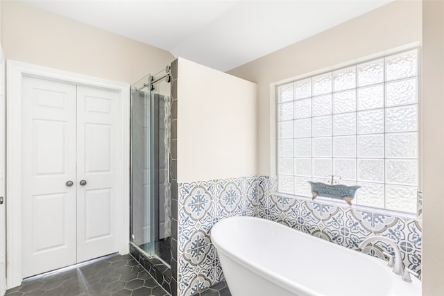 bathroom with tile patterned floors, separate shower and tub, and tile walls