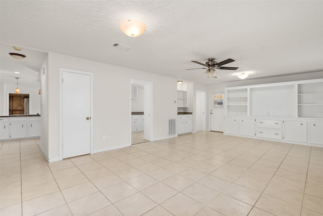 unfurnished living room featuring a textured ceiling, built in features, light tile patterned floors, and ceiling fan