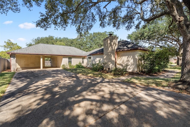 view of front of house with an attached carport, driveway, and a chimney