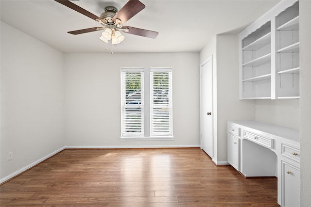 interior space featuring ceiling fan, dark hardwood / wood-style flooring, and built in desk