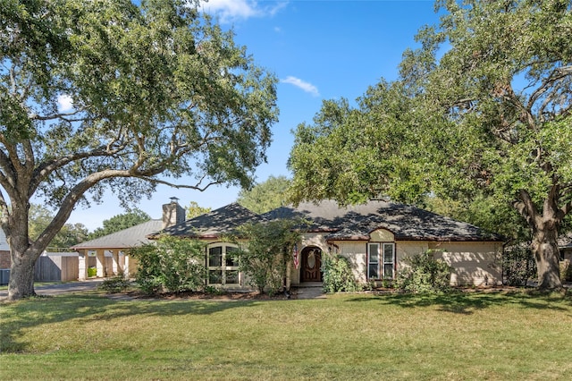 ranch-style house featuring a chimney and a front lawn