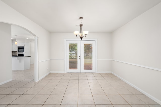 tiled empty room featuring french doors and an inviting chandelier