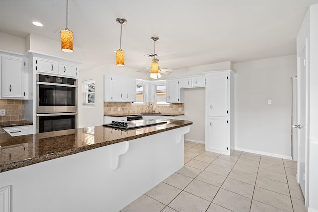 1133 Sally Anne Dr, Rosenberg, TX 77471 - kitchen with double oven, backsplash, a peninsula, a ceiling fan, and white cabinets