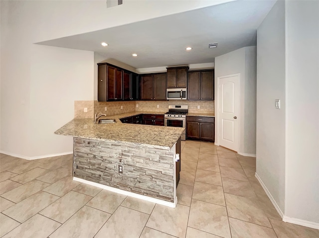 kitchen featuring light stone counters, stainless steel appliances, tasteful backsplash, sink, and kitchen peninsula