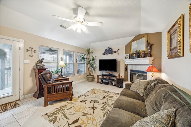 living room featuring ceiling fan, a tile fireplace, light tile patterned floors, and vaulted ceiling