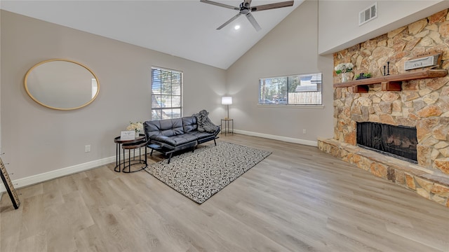 living room with light wood-type flooring, a fireplace, ceiling fan, and high vaulted ceiling