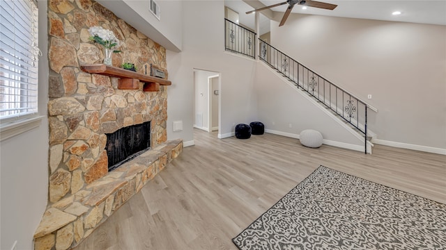 living room with high vaulted ceiling, a fireplace, ceiling fan, and light hardwood / wood-style floors