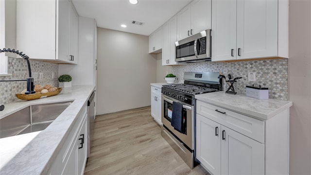 kitchen featuring appliances with stainless steel finishes, white cabinetry, and sink