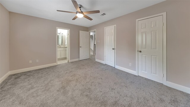 unfurnished bedroom with ceiling fan, ensuite bath, and light carpet