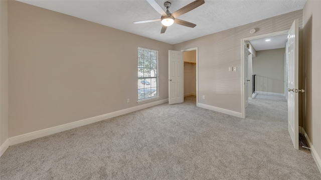 unfurnished bedroom with ceiling fan, light colored carpet, a closet, and a spacious closet