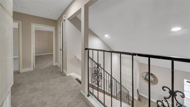 hall featuring lofted ceiling and light carpet