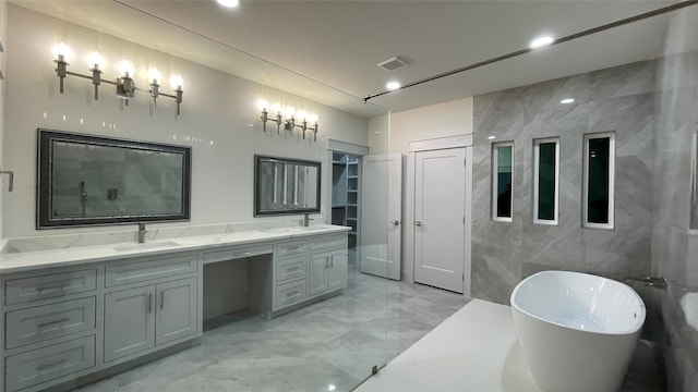 bathroom with a bathing tub, vanity, and tile walls