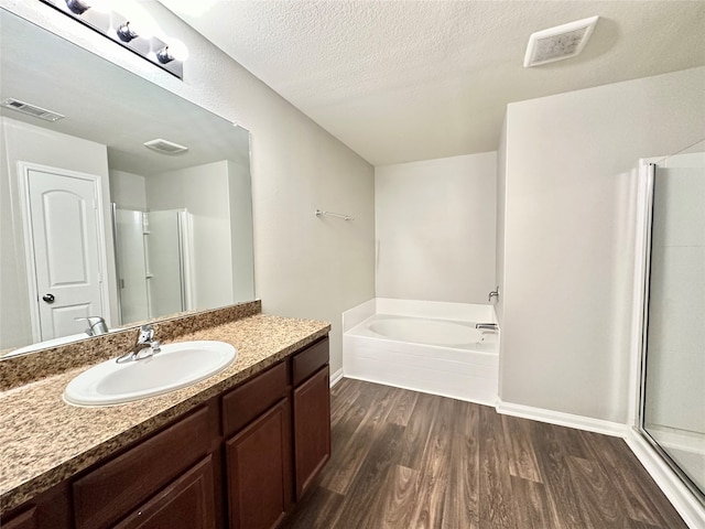 bathroom featuring vanity, plus walk in shower, hardwood / wood-style floors, and a textured ceiling