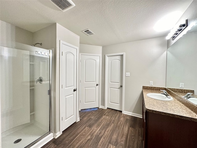 bathroom featuring hardwood / wood-style floors, a shower with shower door, vanity, and a textured ceiling