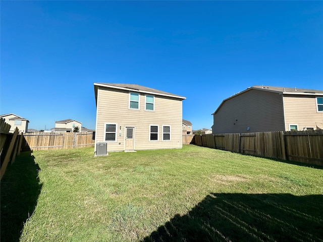 rear view of house with central AC and a lawn