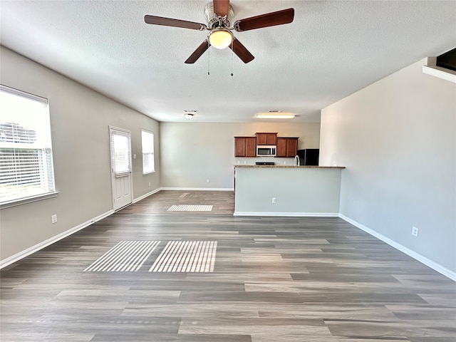 unfurnished living room with dark wood-type flooring, ceiling fan, and a textured ceiling