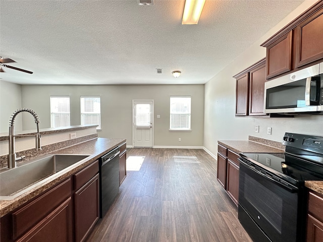 kitchen featuring dark wood-type flooring, sink, stainless steel appliances, and a textured ceiling