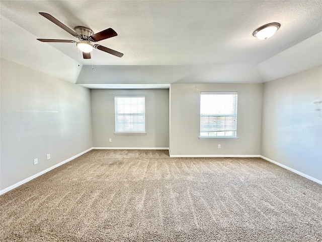 empty room with plenty of natural light, vaulted ceiling, and carpet flooring