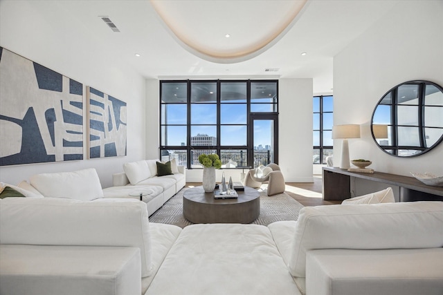 living area featuring recessed lighting, a city view, wood finished floors, visible vents, and a tray ceiling