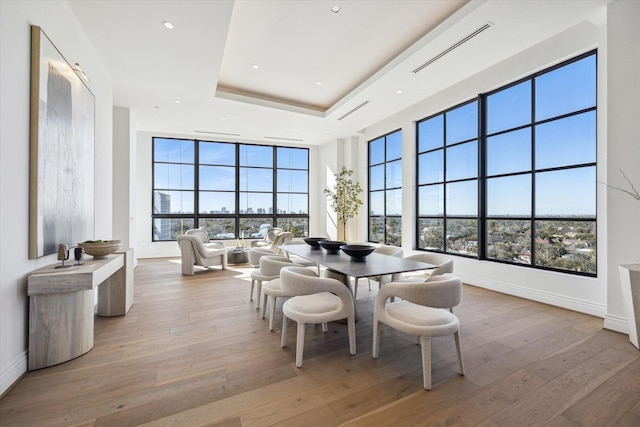 dining room with hardwood / wood-style flooring, baseboards, and a tray ceiling