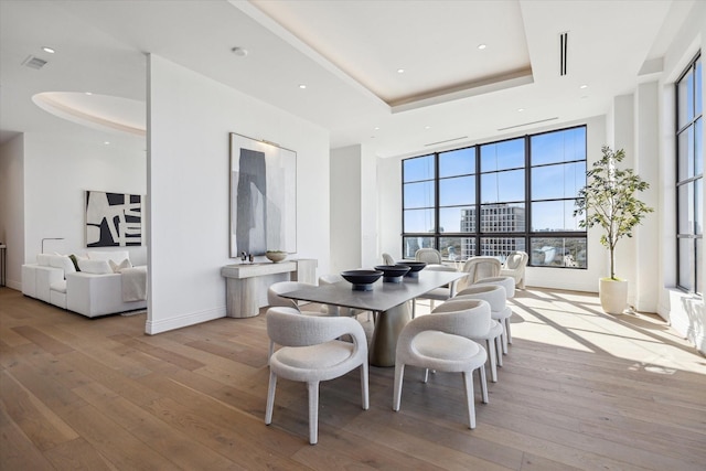 dining room featuring a tray ceiling, wood-type flooring, and baseboards