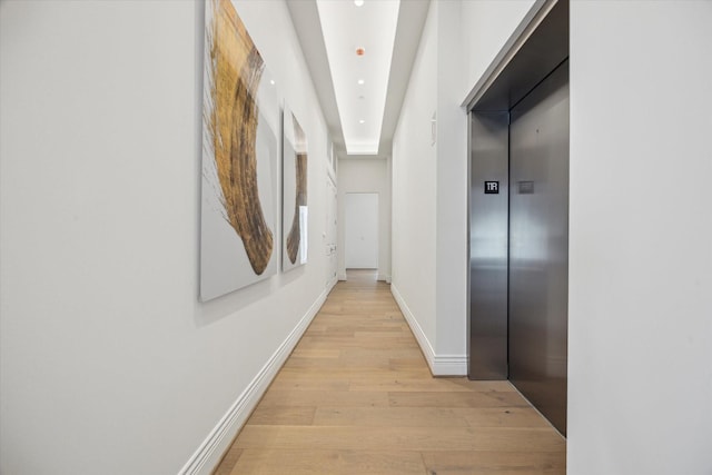 hallway with recessed lighting, elevator, baseboards, and light wood finished floors