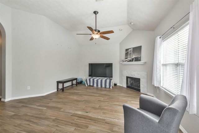 living room with hardwood / wood-style floors, a fireplace, ceiling fan, and vaulted ceiling