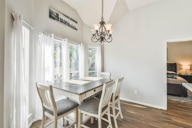 dining area featuring dark wood-type flooring, an inviting chandelier, and vaulted ceiling