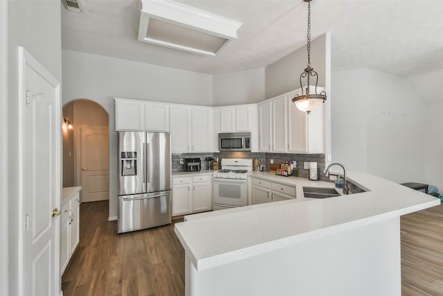 kitchen featuring white cabinets, decorative light fixtures, backsplash, stainless steel appliances, and dark hardwood / wood-style flooring