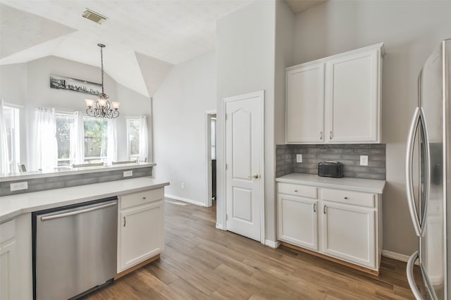 kitchen featuring lofted ceiling, stainless steel appliances, light hardwood / wood-style floors, a notable chandelier, and white cabinetry