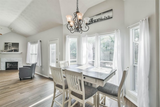 dining area with a notable chandelier, lofted ceiling, and light hardwood / wood-style floors