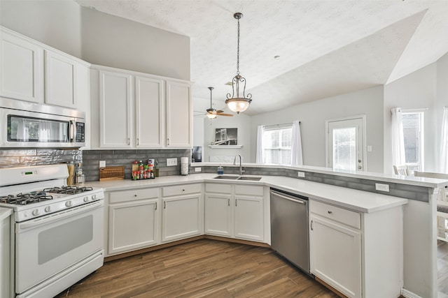 kitchen with stainless steel appliances, hanging light fixtures, sink, and white cabinetry