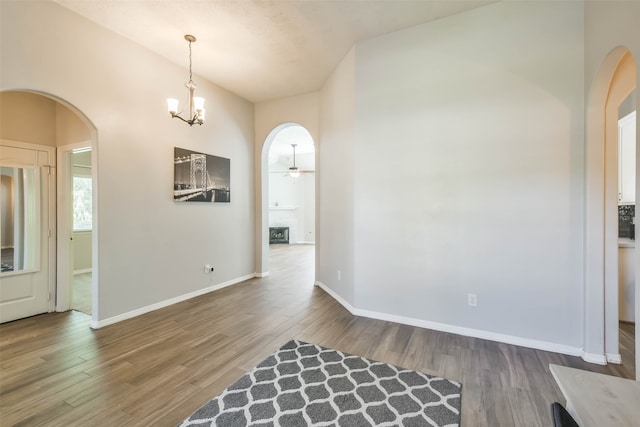 unfurnished dining area with wood-type flooring and ceiling fan with notable chandelier