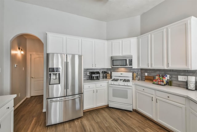 kitchen with stainless steel appliances, white cabinets, decorative backsplash, and dark wood-type flooring