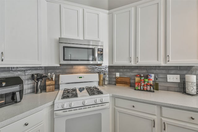 kitchen with light stone counters, white cabinets, tasteful backsplash, and white gas range