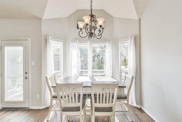 dining area featuring an inviting chandelier, wood-type flooring, and vaulted ceiling