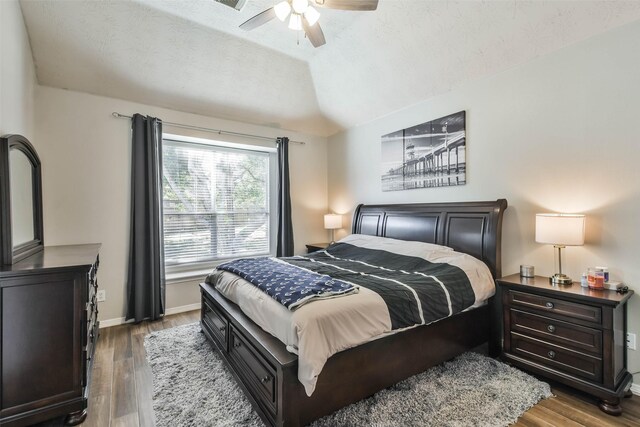 bedroom with lofted ceiling, hardwood / wood-style floors, a textured ceiling, and ceiling fan