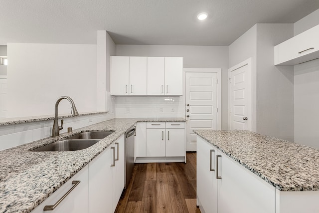 kitchen with dark wood-type flooring, sink, dishwasher, light stone countertops, and white cabinets