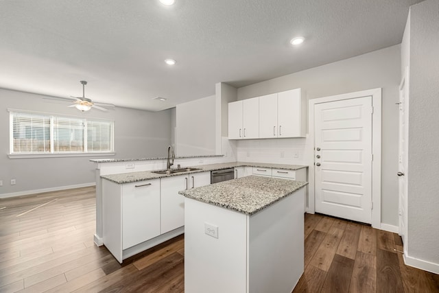 kitchen with a center island, white cabinetry, stainless steel dishwasher, and sink